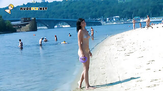 An adorable nudist girls strolls around on the beach and lies down naked